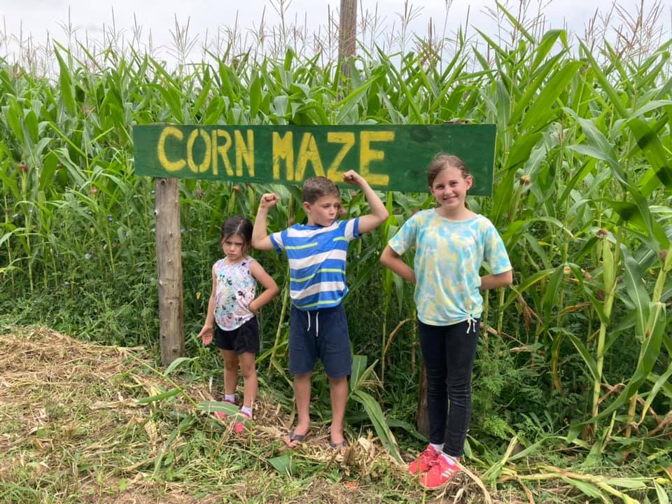 Children standing by the corn maze sign